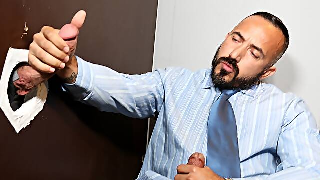 Doominant man plays with a businessman at the glory hole