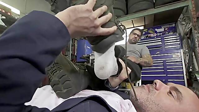 Businessman tongues car mechanics feet while taunting giant dick